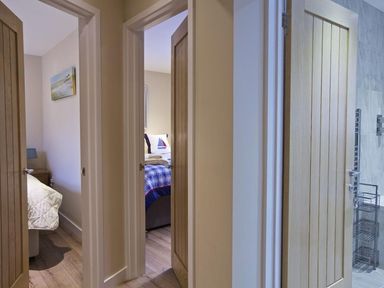 A hallway showing three open doors leading to two bedrooms and a bathroom at Crowthers in Dartmouth
