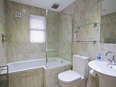 A bathroom with a bathtub shower combination toilet sink and a window at Crowthers in Dartmouth