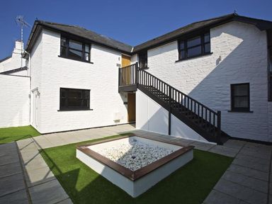 A courtyard with white stone walls black windows and a staircase at Crowthers in Dartmouth