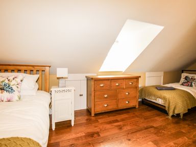 A bedroom with two beds a white nightstand with a lamp and a wooden dresser under a skylight window at Seaside House in Weymouth