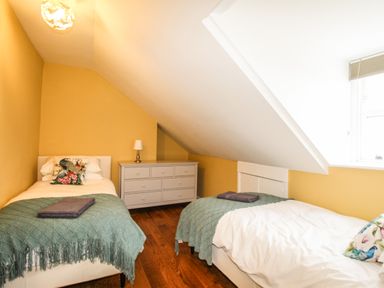 A bedroom with two single beds a chest of drawers and a window at Seaside House Weymouth
