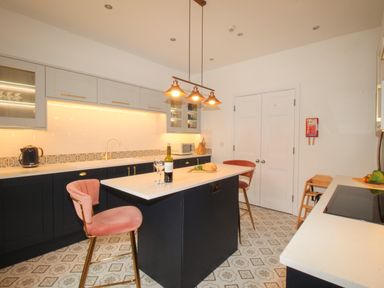 A kitchen with a central island and two pink chairs at Seaside House in Weymouth
