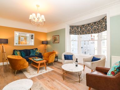 A living room with various armchairs a sofa a coffee table and a large window at Seaside House in Weymouth
