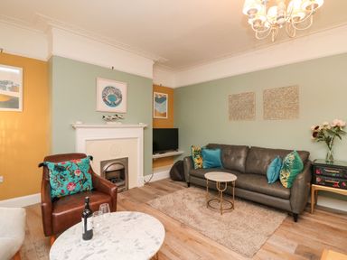 A living room with a brown leather armchair and a gray sofa with cushions by a fireplace at Seaside House in Weymouth