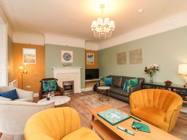 A living room with yellow armchairs a gray sofa a fireplace and a chessboard on a wooden table at Seaside House in Weymouth