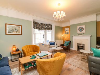 A living room with chairs around tables and a fireplace at Seaside House in Weymouth