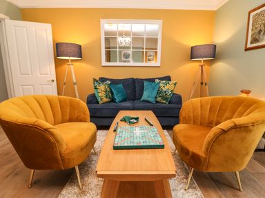 A living room with two mustard yellow armchairs a blue sofa with cushions a wooden coffee table and two floor lamps at Seaside House in Weymouth