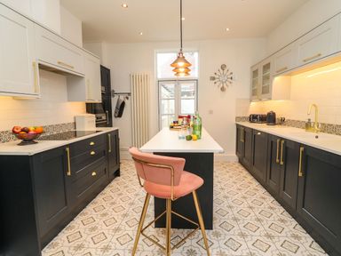 A kitchen with black and white cabinets a patterned tile floor and a pink bar stool at Seaside House in Weymouth