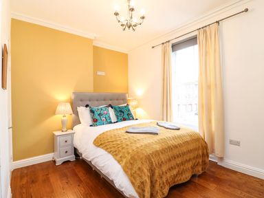 A bedroom with a bed bedside tables lamps and a window at Seaside House in Weymouth