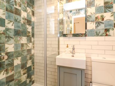 A bathroom with a shower enclosure a sink with a cabinet a toilet and tiled walls at Seaside House in Weymouth