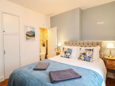 A bedroom with a double bed covered with a blue blanket and two folded towels at Seaside House in Weymouth