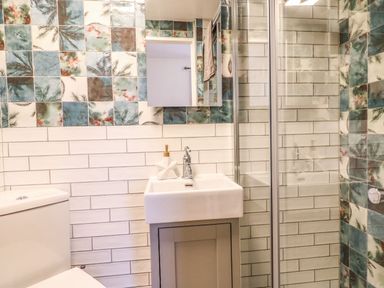 A bathroom with a toilet sink mirror and glass shower door at Seaside House in Weymouth