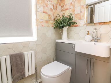 A bathroom with a toilet sink cabinet towel radiator and a window at Seaside House in Weymouth