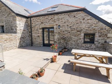 An outdoor patio with potted plants and a wooden picnic table at The Hayloft in Helland near Bodmin