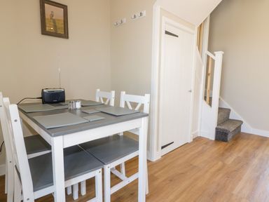 A dining area with a table and four chairs next to a staircase and a closed door at The Hayloft in Helland near Bodmin
