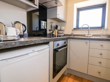 A kitchen with a countertop stove oven sink and window at The Hayloft in Helland near Bodmin