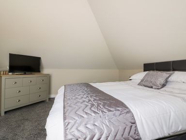A bedroom with a bed and a dresser with a television on it at The Hayloft in Helland near Bodmin