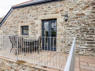 A stone wall balcony with metal railing table and chairs at The Hayloft in Helland near Bodmin