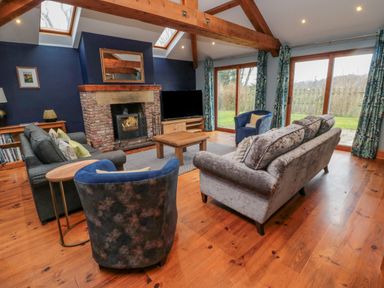 A living room with sofas a fireplace a television and large windows at Ridley Lodge West Thirston felton