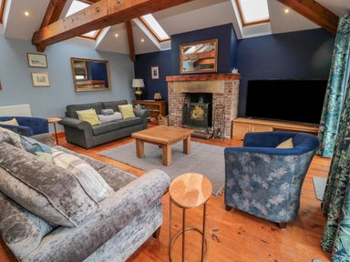 A living room with sofas chairs a wooden coffee table a fireplace and a television at Ridley Lodge West Thirston felton