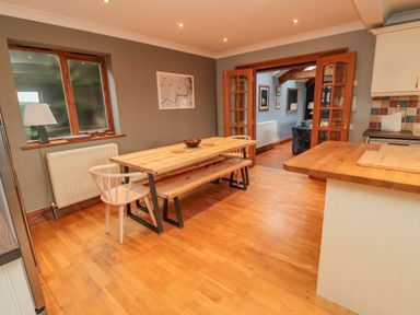 A dining area with a wooden table bench chair and lamp near a window at Ridley Lodge in West Thirston felton