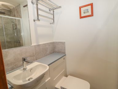 A bathroom with a sink and faucet a shower with glass door a towel rack and a framed picture on the wall at Ridley Lodge in West Thirston felton