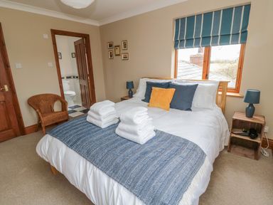 A bedroom with a bed with towels and pillows and a window with blue striped blinds at Ridley Lodge in West Thirston felton