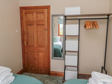 A bedroom corner with wood door mirror open closet with hangers and storage bins at Ridley Lodge in West Thirston felton
