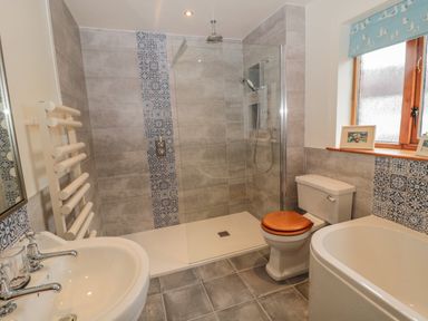 A bathroom with a shower, toilet, sink, bathtub, and window at Ridley Lodge in West Thirston felton