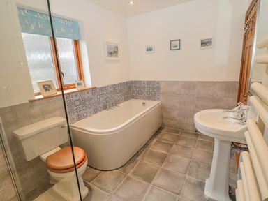 A bathroom with a bathtub toilet and pedestal sink at Ridley Lodge in West Thirston felton