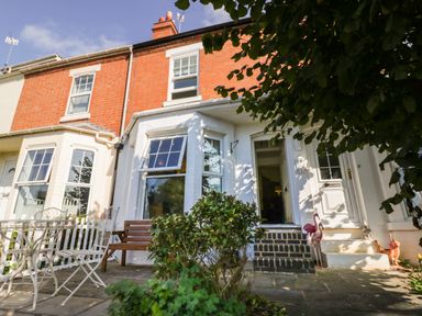 A patio area with metal table and chairs wooden bench plants and entrance doors at Florence Villas in Worcester