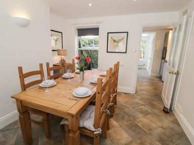 A dining room with a wooden table set for six people and framed deer artwork on the walls at Florence Villas in Worcester