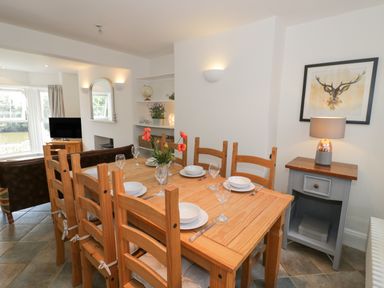 A dining area with a wooden table set with plates and glasses next to a small side table with a lamp and a framed deer picture at Florence Villas in Worcester