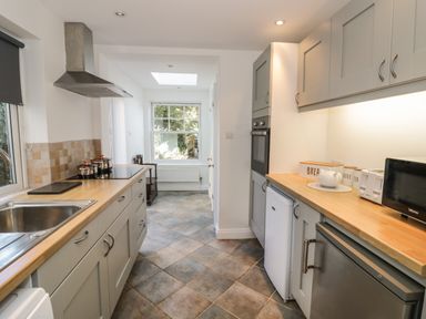 A galley kitchen with light wooden countertops gray cabinets stainless steel sink and appliances at Florence Villas in Worcester