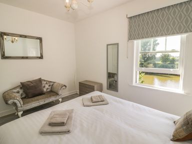 A bedroom with a bed with folded towels a decorative sofa a mirror and a window with a view at Florence Villas in Worcester