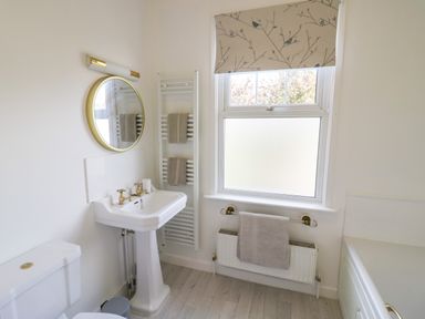 A bathroom with a pedestal sink mirror and towels near a window at Florence Villas in Worcester