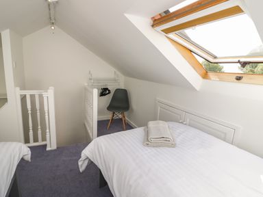 A bedroom with two single beds a skylight window a black chair and a small closet at Florence Villas in Worcester