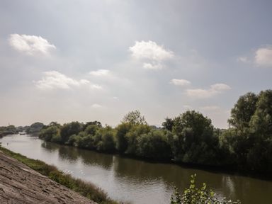 A river with trees along the banks under a partly cloudy sky at Florence Villas in Worcester