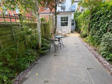 A garden patio with chairs and tables surrounded by greenery at Florence Villas in Worcester
