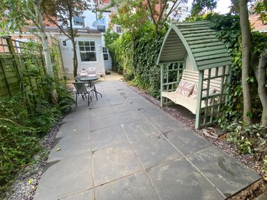 A backyard patio with a covered bench and two tables with chairs at Florence Villas in Worcester