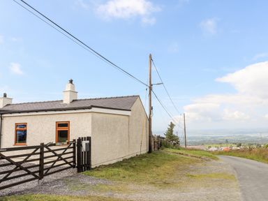 A country house near a road with power lines and a gate at Penrallt Fawr in Rhosgadfan near Waunfawr