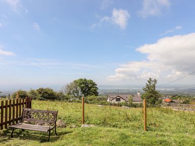 A garden bench near a fence overlooking houses and green fields at Penrallt Fawr in Rhosgadfan near Waunfawr