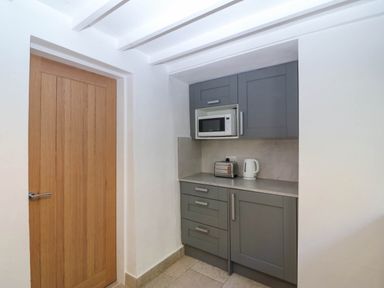 A kitchen with a microwave, toaster, and kettle at 4 Bryn Llan, Aberdaron