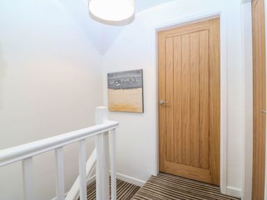 A hallway with a staircase and doors at 4 Bryn Llan Aberdaron