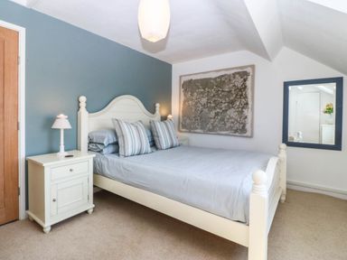 A bedroom featuring a bed, nightstand, and mirror at 4 Bryn Llan, Aberdaron