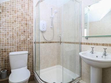 A bathroom with a shower, toilet, and sink at 4 Bryn Llan in Aberdaron