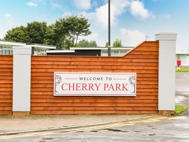 A wooden fence with a welcome to Cherry Park sign and white pillars at 57 Cherry Park in Chapel St Leonards