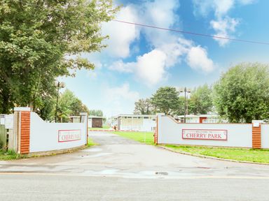 The entrance gates to Cherry Park with a driveway leading inside and trees on either side at 57 Cherry Park in Chapel St Leonards