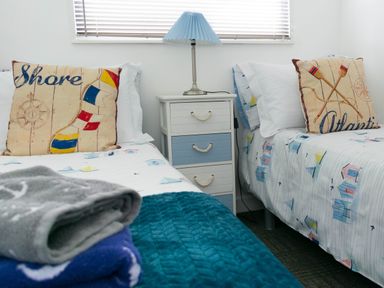 A bedroom with two beds separated by a nightstand with a lamp at 57 Cherry Park in Chapel St Leonards