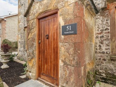A wooden door set in a stone wall with a plaque reading 51 Norden House